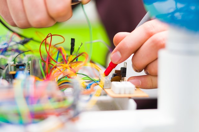 Closeup photo of an electrician's hands using multimeter for detecting electrical failure.