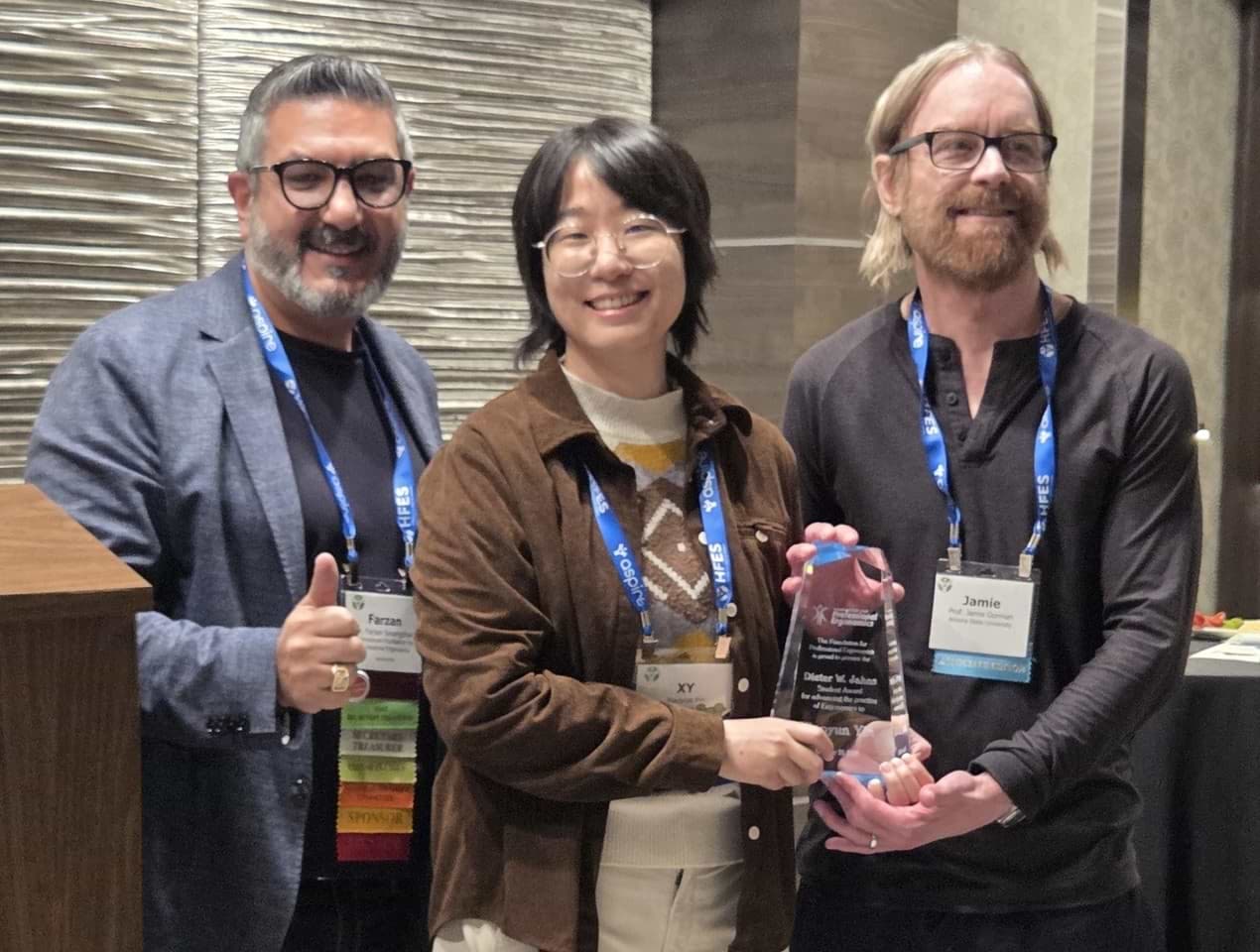 IFPE President Farzan Sasangohar (left) presents the DWJ award to Xiaoyun Yin. Professor Jamie Gorman (right) is Xiaoyun’s major professor.